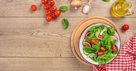 Spinach salad with fresh tomato, onion, green leaves mix. Healthy vegan food. Top view