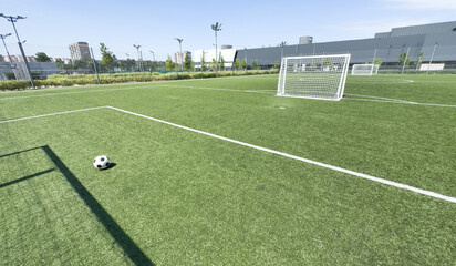 Soccer ball on artificial bright and dark green grass at public outdoor football stadium