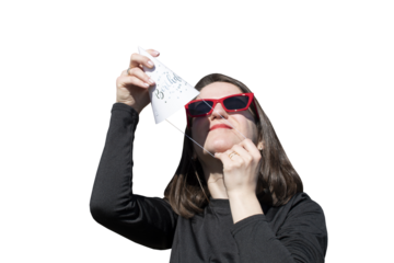 A young woman in red eyeglasses puts on a hat for birthday party isolated