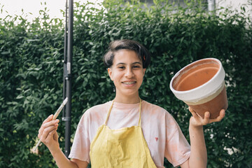 Happy and proud teenage girl showing the clay pot she is painting