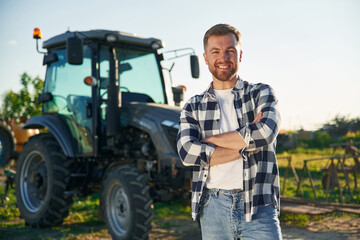 Standing near tractor. Adult farmer is outdoors