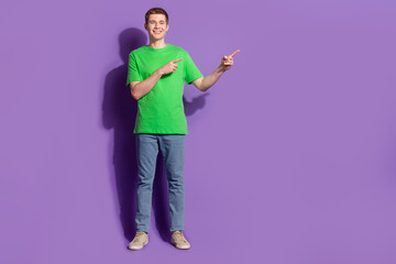 Full size photo of nice young man direct fingers empty space wear t-shirt isolated on violet color background