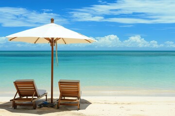 A photo of a beach with clear blue water and white sand, featuring sun loungers under an umbrella. The composition evokes a sense of luxury travel, relaxation and vacation.