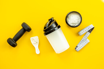 Sports nutrition - protein shaker and black dumbbells, top view