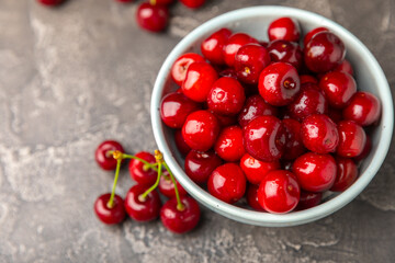 Cherries. Fresh ripe cherries with leaves on a textured wooden background. Fresh sweet organic cherry pile. Berries and fruits. Vegan. Healthy eating. Place for text. Copy space
