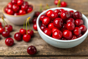 Cherries. Fresh ripe cherries with leaves on a textured wooden background. Fresh sweet organic cherry pile. Berries and fruits. Vegan. Healthy eating. Place for text. Copy space