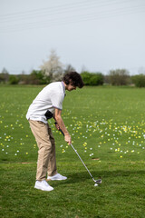 Dark-haired young guy playing gold and looking excited