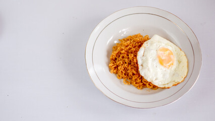 Fried noodles with fried egg and red cayenne pepper. Served on a serving white plate. Isolated on white background.