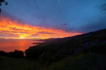 A beautiful sunset over the ocean with a mountain in the background