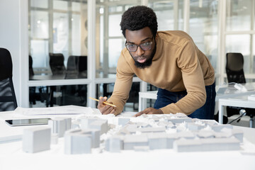 African american architect thinking on a miniature and looking thoughtful