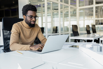 Young dark-skinned man working on the laptop in the office