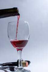 A bottle is pouring red wine into a glass on a table
