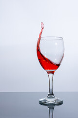 A wine glass containing a splash of red liquid, such as wine or fruit syrup