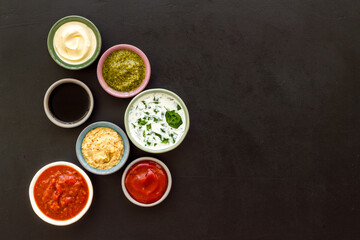 Set of sauces in bowls - pesto salsa mustard and others. Food background
