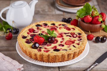 Tart with cherries strawberries and custard milk cream filling. Open cheesecake pie. Delicious homemade summer dessert with berries. 