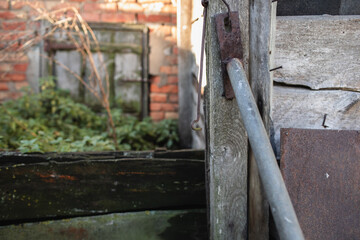 an old wooden fence with a large metal hook. Abandoned building in a village where people do not live