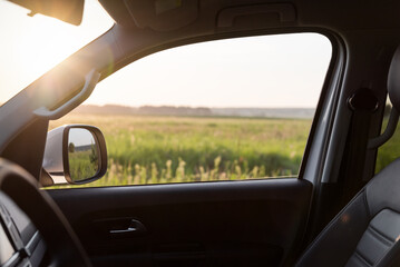 Car side window. Looking at the green meadow in the background through front passenger door.