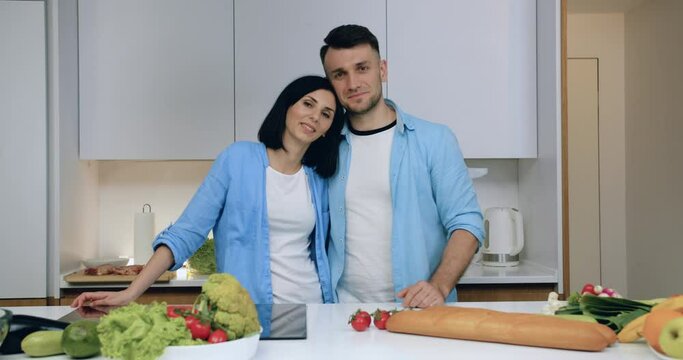 Happy smiling woman and man married couple looking at camera in love standing on kitchen background