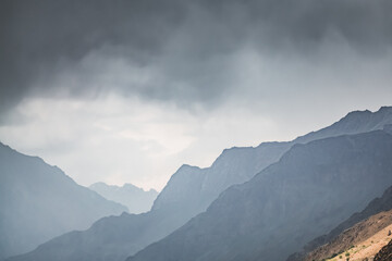 Silhouette of Tien Shan rocky mountain range against cloudy sky in Pamir in Tajikistan mountains, minimalistic abstract landscape of mountains for background