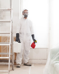Professional mold removal service: Worker wearing protective suit, gloves and respirator mask,...