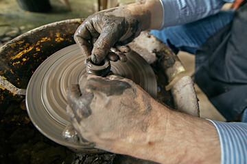 Hands of craftsman artist working on pottery wheel.