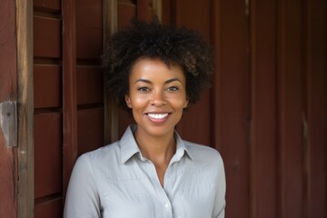 Portrait of a happy afro-american woman in her 50s donning a classy polo shirt over rustic wooden...