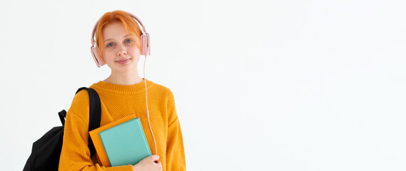 Young college going european redhead hair female nerd student with a backpack, headphones on head,...