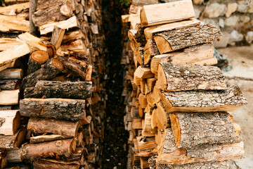 Rustic firewood stack against stone wall on a sunny day