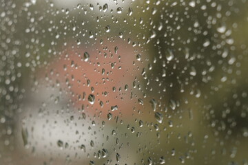 Raindrops on window with blurry background. Close up of water droplets on glass with selective focus.