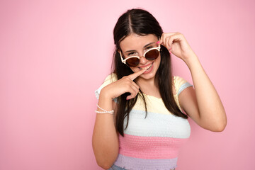 Naklejka premium Young beautiful woman looking at camera.Trendy girl in casual summer white T-shirt and jeans shorts in round sunglasses. Positive female shows facial
