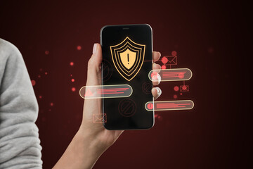 Close up of female hand holding smartphone with abstract digital web security error alert on dark red background. Online safety and protection concept, hacker attack.