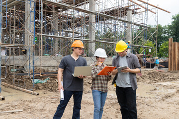 Team of construction workers discussing project details with blueprint in construction site.