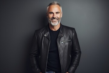 Obraz premium Portrait of a happy man in his 50s sporting a classic leather jacket on modern minimalist interior