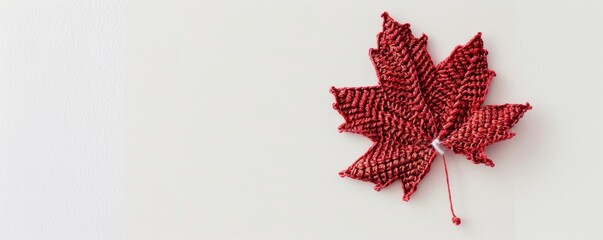 Red knitted maple leaf on white background, handmade craft. Autumn decoration concept