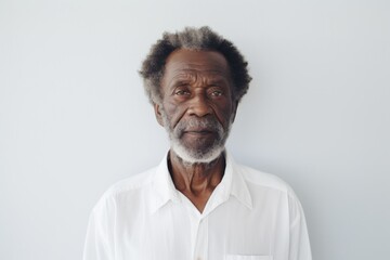 Obraz premium Portrait of a blissful afro-american elderly 100 years old man wearing a classic white shirt isolated in modern minimalist interior