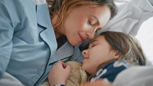 Awake parent toddler bonding cozy bed in pyjamas closeup. Woman stroking girl