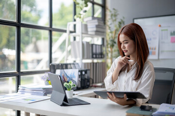 Obraz premium A woman is sitting at a desk with a laptop and tablet in front of her