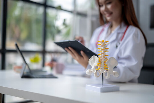 A woman in a white lab coat is sitting at a desk with a clipboard