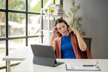 Obraz premium A woman is sitting at a desk with a laptop and a tablet