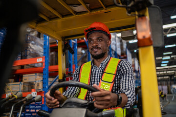 A man in a yellow vest is driving a forklift in a warehouse. He is smiling and he is enjoying his job © KANGWANS