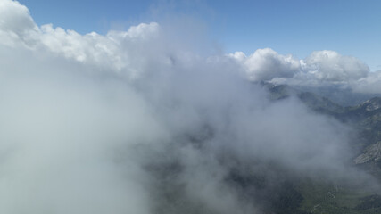 foreground mountain capped by cloud, background boasts blue sky dotted with white clouds