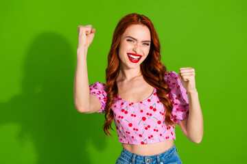 Photo of shiny lucky lady dressed print top rising fists empty space isolated green color background