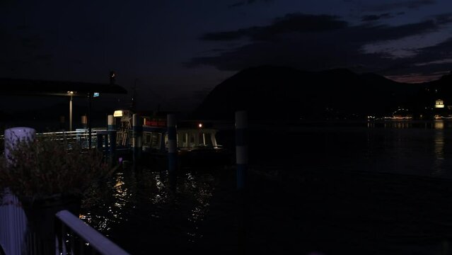Traghetto arriva al porticciolo di Sulzano, luci accese al tramonto, sullo sfondo a destra si vede porto Maraglio a Monte isola