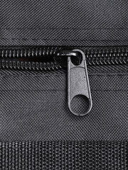 Half open zipper with a lock on the textile surface of a bag, background