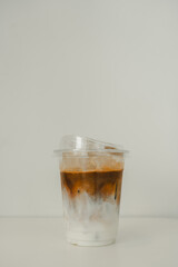 Cold iced latte coffee, showing separate in a layer the bottom as milk top by coffee shot in a plastic glass 16oz.