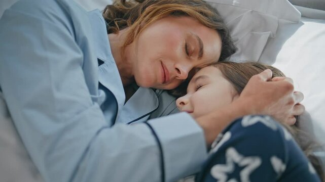 Smiling lady stroking kid girl bed lazy morning closeup. Woman embracing child