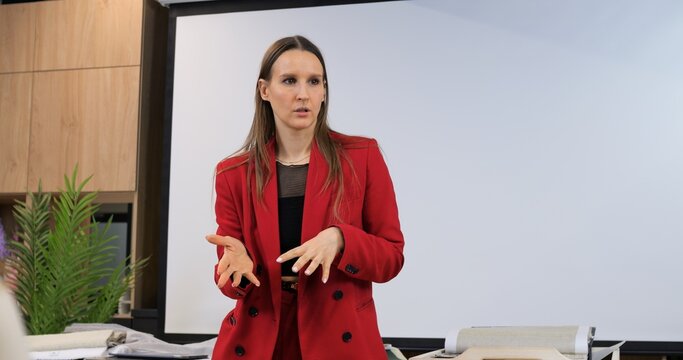 Confident woman in red blazer leading business presentation. Showcasing strong leadership and professionalism, inspiring audience with her assertive and commanding presence in business environment