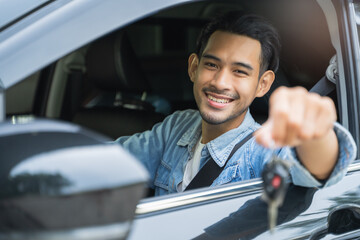 Happy client smiling and showing key car while sitting in new vehicle