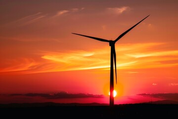 Obraz premium A silhouette of a wind turbine against a vibrant sunset backdrop.