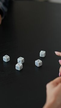 In the image, a person is intensely engaged in playing a dice game, showing focus and concentration